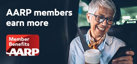 An older woman looks at her phone with coffee in her hand
