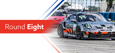 Round eight race featuring a dark grey Porsche with red and black racing stripes on the track.